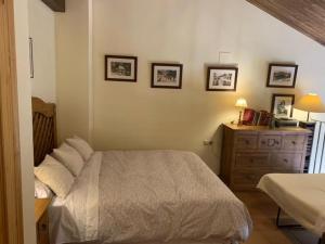a bedroom with a bed and a dresser and pictures on the wall at Apartamentos Sol Valdelinares in Valdelinares