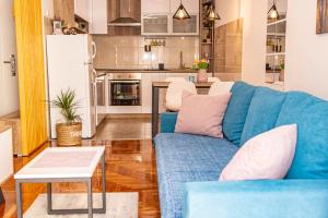 a living room with a blue couch and a kitchen at Harizma apartmani in Kragujevac