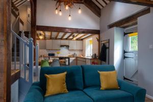 a living room with a blue couch and a kitchen at Barn Retreat with Valley Views & Onsite Dog Field in Bryn-crug