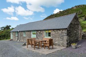 a stone cottage with a table and chairs in front of it at The Cowshed in Bryn-crug