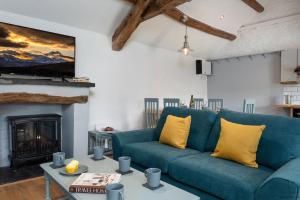 a living room with a blue couch and a fireplace at The Cowshed in Bryn-crug