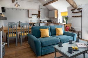 a living room with a blue couch and a kitchen at The Cowshed in Bryn-crug
