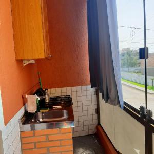 een kleine keuken met een wastafel en een raam bij Residencial dos Moleques in Capão da Canoa