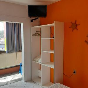 un estante de libros blanco en una habitación con una pared de color naranja en Residencial dos Moleques en Capão da Canoa
