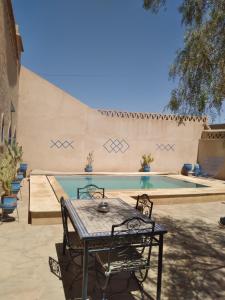 a table and chairs next to a swimming pool at Maison Mirage B&B in Hassilabied