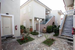 a courtyard of a house with a white door and stairs at Remvi Hotel - Apartments in Stoupa