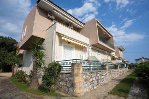 a building with a stone wall next to a house at Remvi Hotel - Apartments in Stoupa