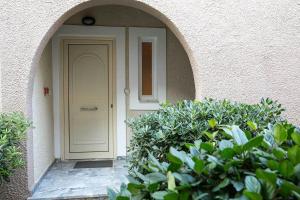 an entrance to a building with a white door and bushes at Remvi Hotel - Apartments in Stoupa