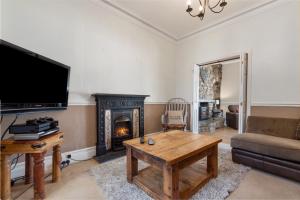 a living room with a fireplace and a tv at Cartref - Beautiful Cottage, Hot Tub, Countryside Views in Saundersfoot