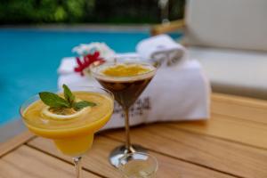 two cocktails sitting on a wooden table with a towel at D'avenue Boutique Hotel Accra in Accra