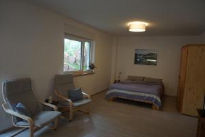 1 dormitorio con 1 cama, 2 sillas y ventana en FeWo am Neckarsteig mit Anbindung an Heidelberg en Neckarsteinach