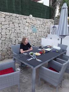 una mujer sentada en una mesa con un plato de comida en Apartment CALISTROS BENITACHELL MINIMUM STAY ONE NIGHT, en Benitachell