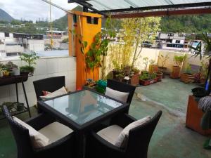 a patio with a glass table and chairs on a balcony at Mayra's Apartments and Spanish School in Baños