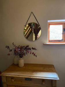 einen Spiegel an einer Wand über einem Tisch mit einer Vase in der Unterkunft Kingpost - 3 bedroom Apartment in Sandwich in Kent