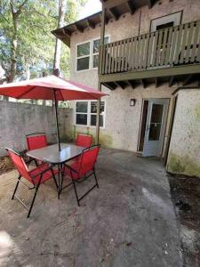 a table and chairs with an umbrella in front of a house at Elegant 2-bedroom pet-friendly villa w 2 parking spaces in Hilton Head Island