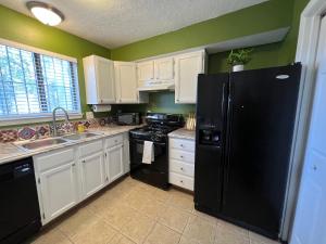 a kitchen with white cabinets and a black refrigerator at The Burque Boho House in Albuquerque