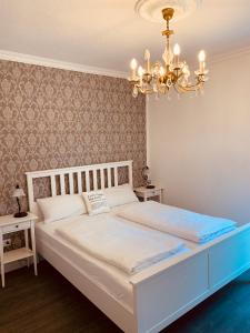 uma cama branca num quarto com um lustre em Villa am Südpark em Bad Nauheim