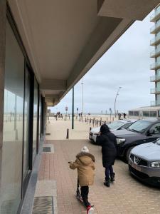 two people walking down a sidewalk near the beach at La Panne Appartement en bord de mer - La Vie Bohème in De Panne