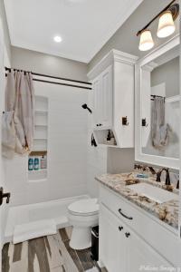 a white bathroom with a toilet and a sink at The Cross Lake Maison in Shreveport