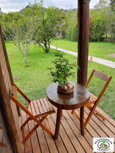 einen Tisch und Stühle auf einer Veranda mit Topfpflanze in der Unterkunft Chalé Recanto Nosso Lar in São Bento do Sapucaí