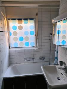 baño con bañera, lavabo y ventana en Appartement avec terrasse, en Sion
