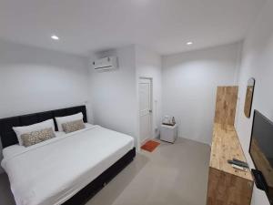 um quarto branco com uma cama e uma televisão de ecrã plano em Vamin Resort Chiangkhan Loei วามินทร์รีสอร์ท เชียงคาน เลย em Chiang Khan