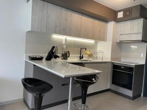 a kitchen with a counter and two black stools at Edificio Curitiba, Apartamento nuevo y céntrico 1B 1D in Temuco