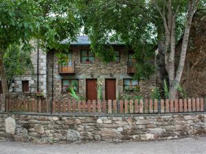 a stone house with a fence in front of it at Casa rural El Trubio in Vigo de Sanabria