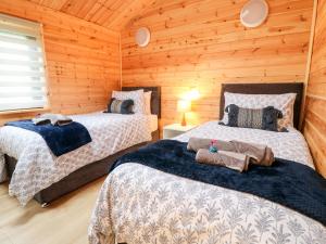 two beds in a room with wooden walls at Castle View Lodge in Derby