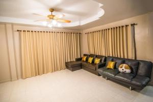 a living room with a black leather couch with yellow pillows at Vanilla house heart of Sattahip in Sattahip