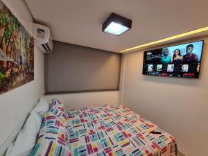 a bedroom with a bed and a tv on the wall at Malawi Muro Alto - Flat 103H Térreo in Porto De Galinhas +40 photos