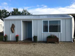 a white shed with a window and potted plants at Vineyard Cottage in Blenheim on the Golden Mile in Blenheim