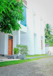 a white building with a red door and two plants at White House Hotel Mirissa in Mirissa