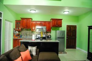 a kitchen with green walls and wooden cabinets and a couch at GK Luxury Apartment in Kingston
