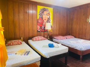 two beds in a room with a painting on the wall at Ricos Beach Cottages in El Nido