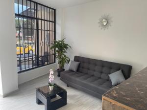 a living room with a black couch and a window at ONE HOTEL in Girardot