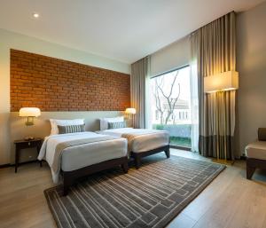 a bedroom with two beds and a brick wall at Marasa Sarovar Premiere, Bodhgaya in Bodh Gaya