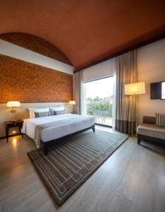 een slaapkamer met een groot bed en een bakstenen muur bij Marasa Sarovar Premiere, Bodhgaya in Bodh Gaya