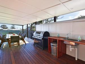 an outdoor kitchen with a grill and a table with a table at The Lobster Pot in Currarong