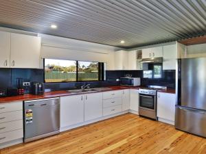 a kitchen with white cabinets and stainless steel appliances at The Lobster Pot in Currarong +14 photos