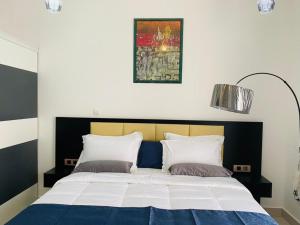 Una cama con dos almohadas y una foto encima. en JANO HOUSE AppartHôtel, en Yibuti