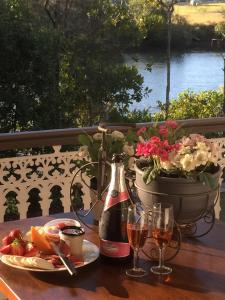 a table with a glass of wine and a plate of food at Bli Bli House Riverside Retreat in Twin Waters