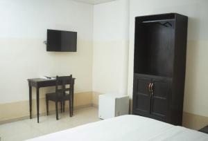 ein Schlafzimmer mit Bett, Schreibtisch und Fernseher in der Unterkunft Hôtel Seaside in Lomé