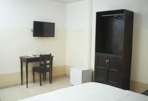 um quarto com uma cama, uma secretária e uma televisão em Hôtel Seaside em Lomé