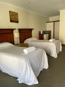 a hotel room with three beds with white sheets at Denmark Hotel in Denmark