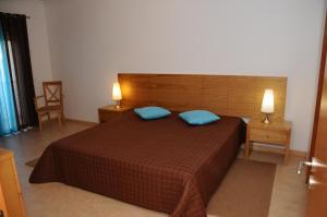 a bedroom with a large bed with two blue pillows at Albufeira Mar Vilas in Albufeira