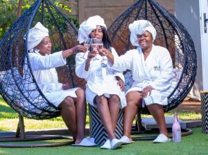 three women in white robes sitting on swings at Ouklip Place Hotels in Roodepoort
