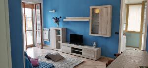 sala de estar con TV en una pared azul en Attico trilocale con solarium a Borghetto Santo Spirito, en Borghetto Santo Spirito