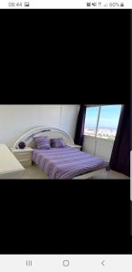 a bedroom with a bed with purple sheets and a window at Appartement Laurent Bonnevay in Villeurbanne