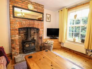a living room with a brick fireplace and a wooden table at Valentine Cottage in Aylsham